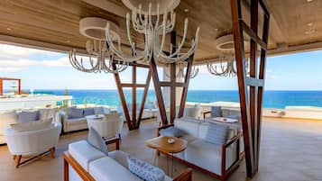 Un amplio espacio al aire libre con mobiliario moderno y una gran araña, con vistas al océano.