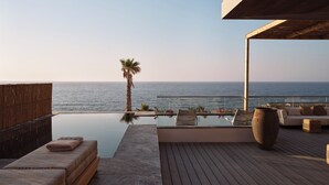 A modern outdoor deck with a pool, lounge chairs, and a view of the ocean. - The Royal Blue (Mylopotamos)
