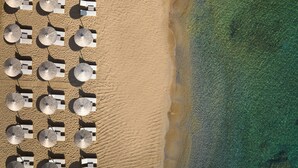 An aerial view of a beach with rows of sun umbrellas and lounge chairs. - The Royal Blue (Mylopotamos)