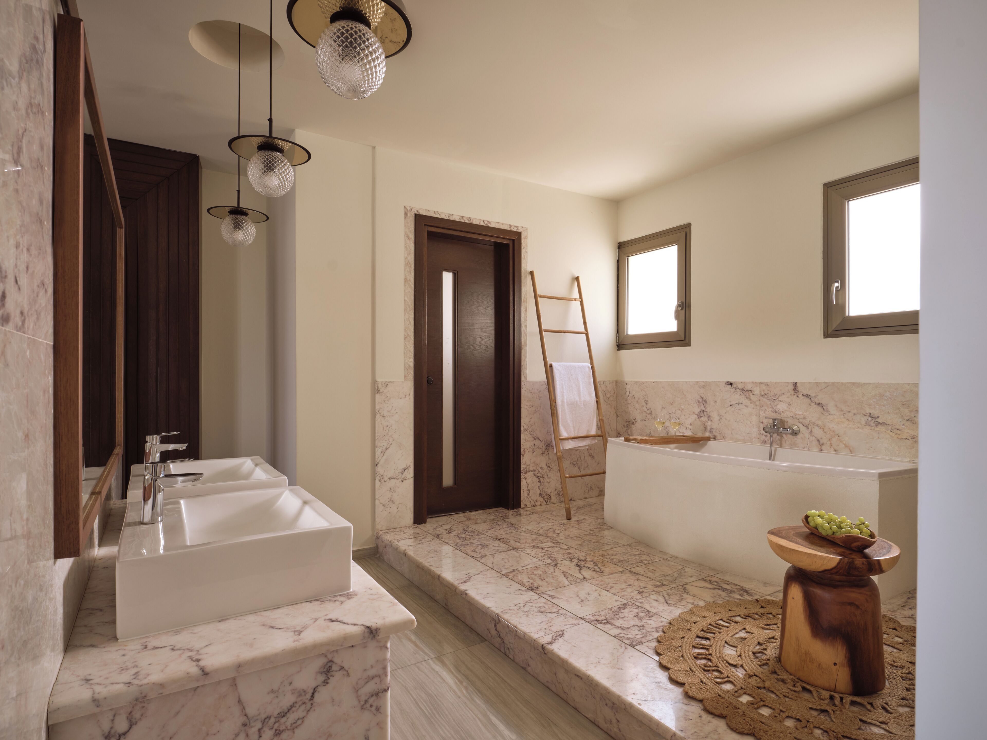 A modern bathroom with a large sink, a bathtub, and a wooden ladder.