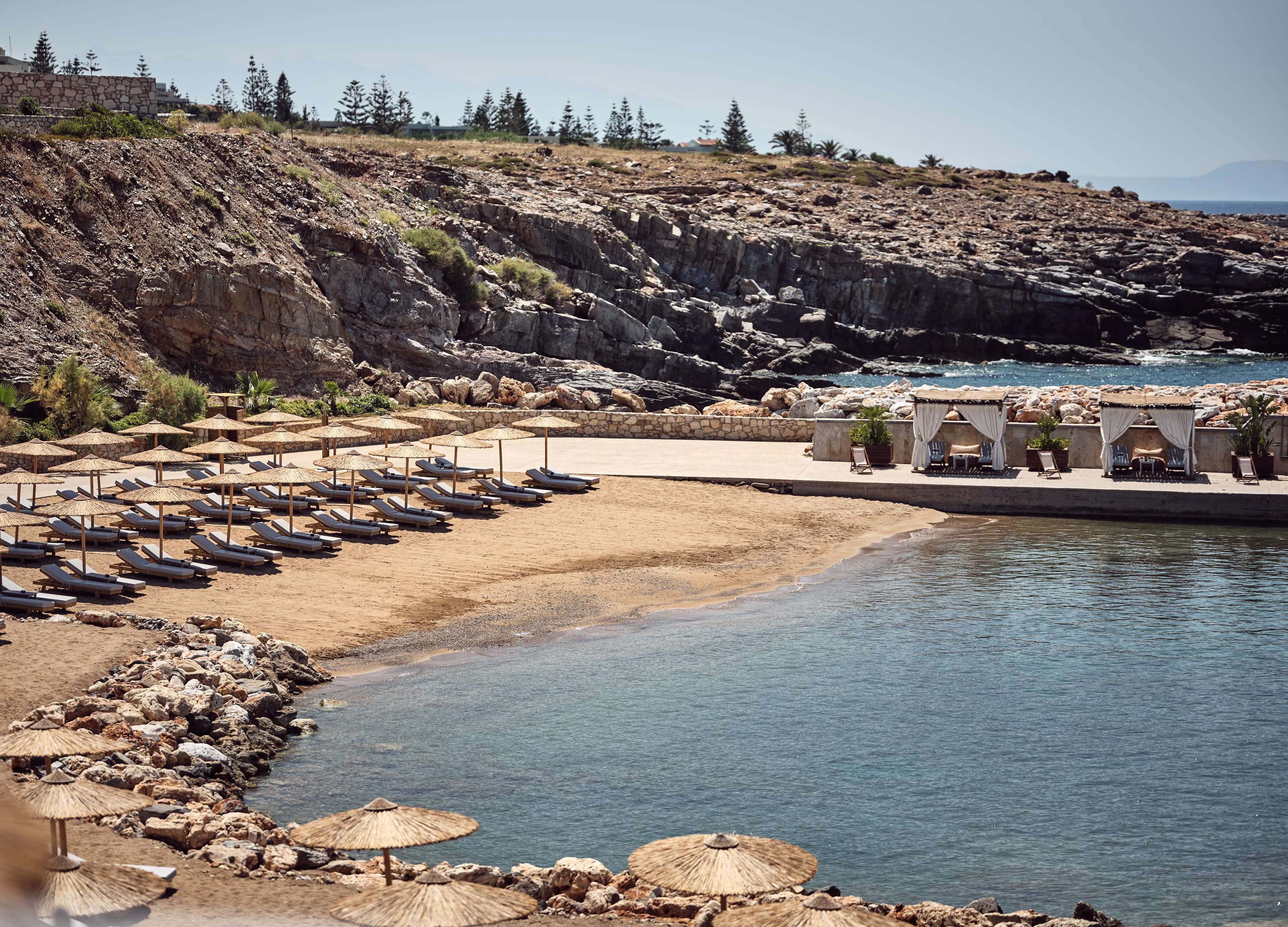 Un complejo turístico en la playa con tumbonas, sombrillas y una zona de piscina.