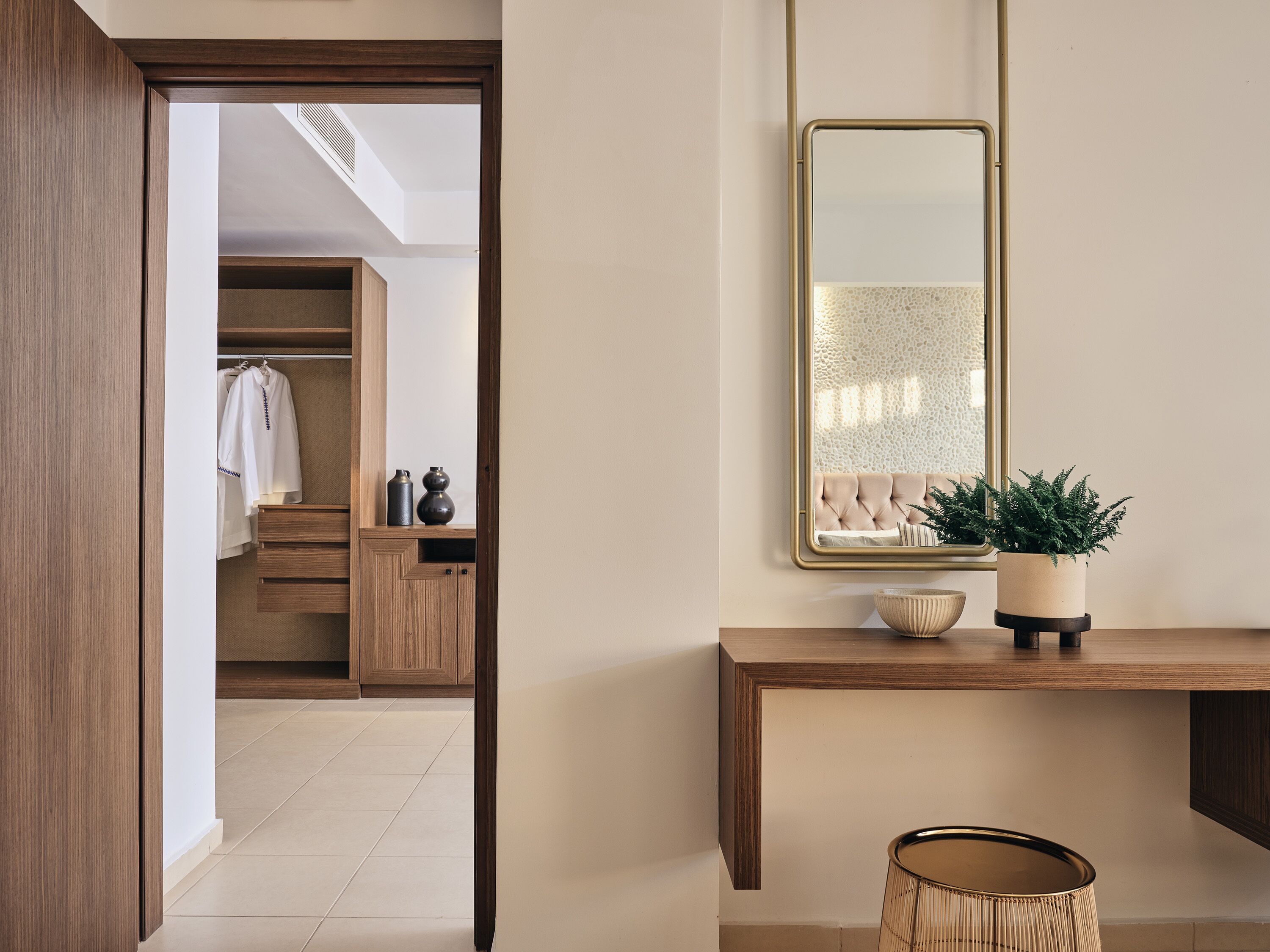 A modern bathroom with a wooden vanity, a mirror, and a potted plant.