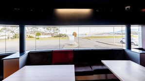 Un intérieur moderne avec de grandes fenêtres, un coin salon et une vue sur un parking et les environs.