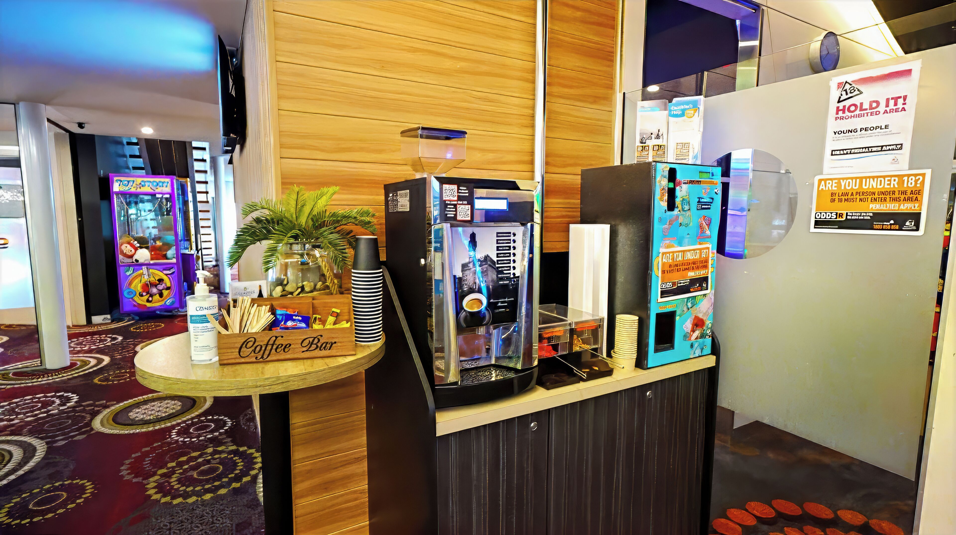 A coffee bar area with a coffee machine, a jar of snacks, and a sign indicating a prohibited area for young people.