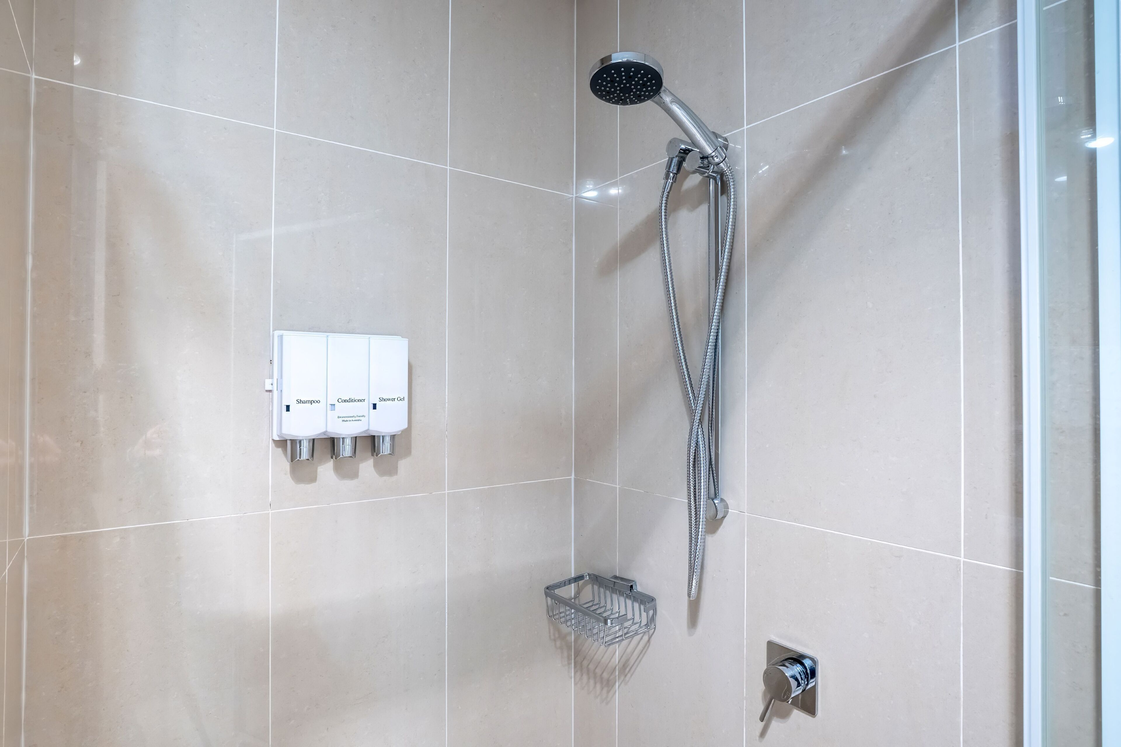 Ein Badezimmer mit Dusche, Handtrockner und Seifenspender.