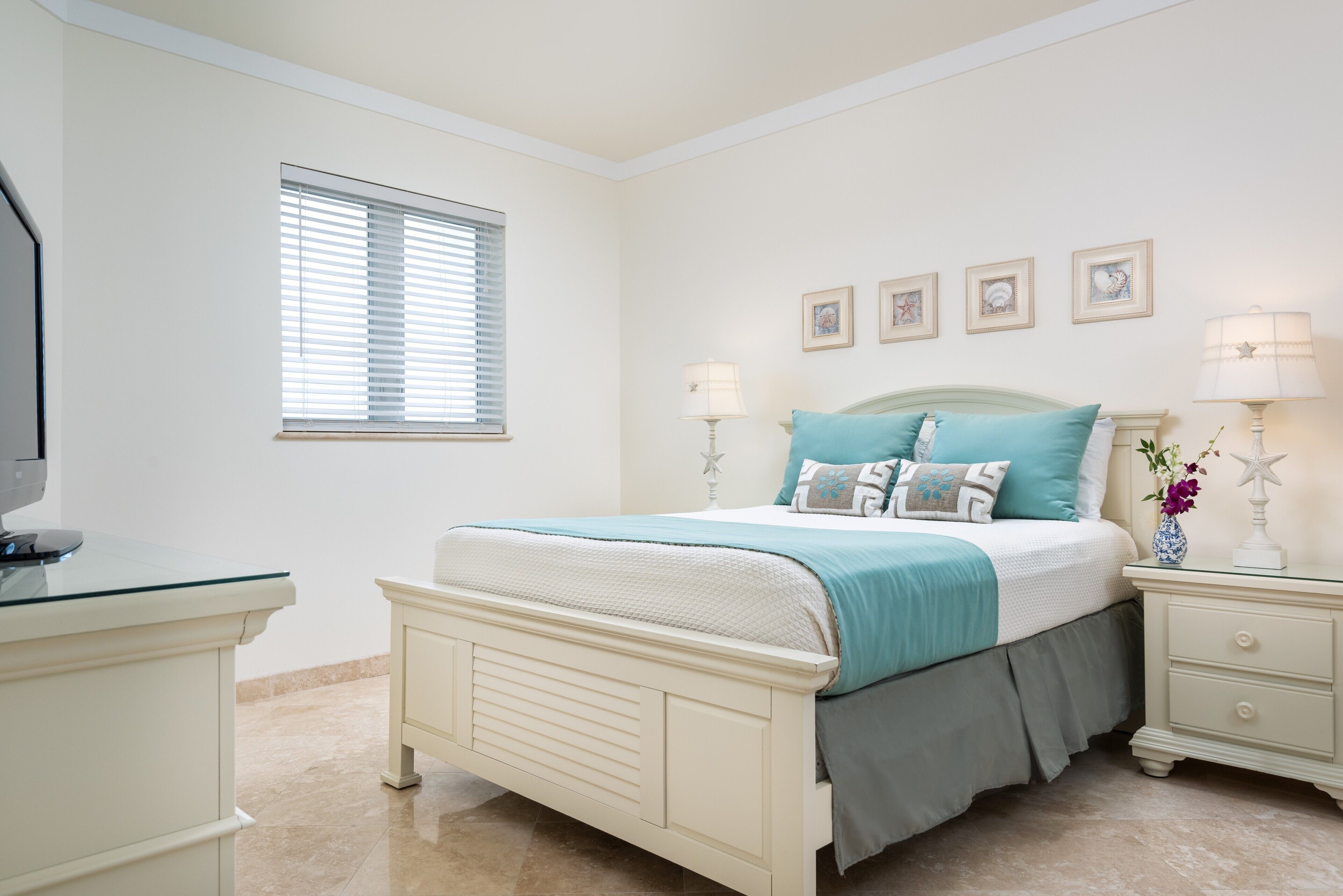 Quarto com cama, mesas de cabeceira, cômoda e janela com persianas.