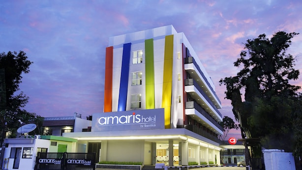 Ein modernes Hotelgebäude mit einer farbenfrohen Fassade und einem Schild, auf dem 'Amaris Hotel by Santika' steht.