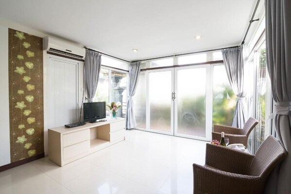 Una sala moderna con un televisor de pantalla plana, un sofá y un comedor con sillas de mimbre.