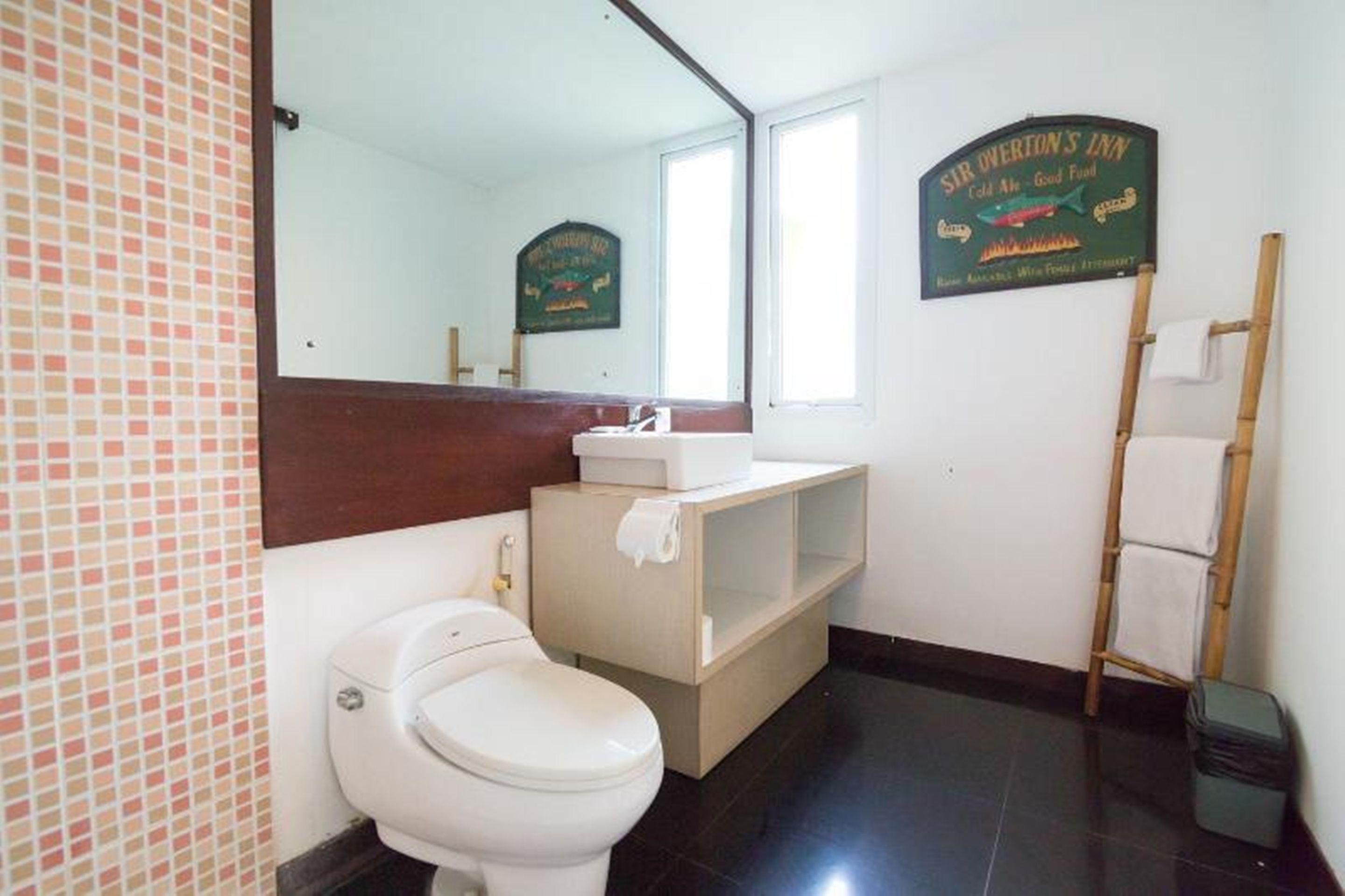 Un baño con inodoro, lavabo, espejo y un cartel sobre el espejo.