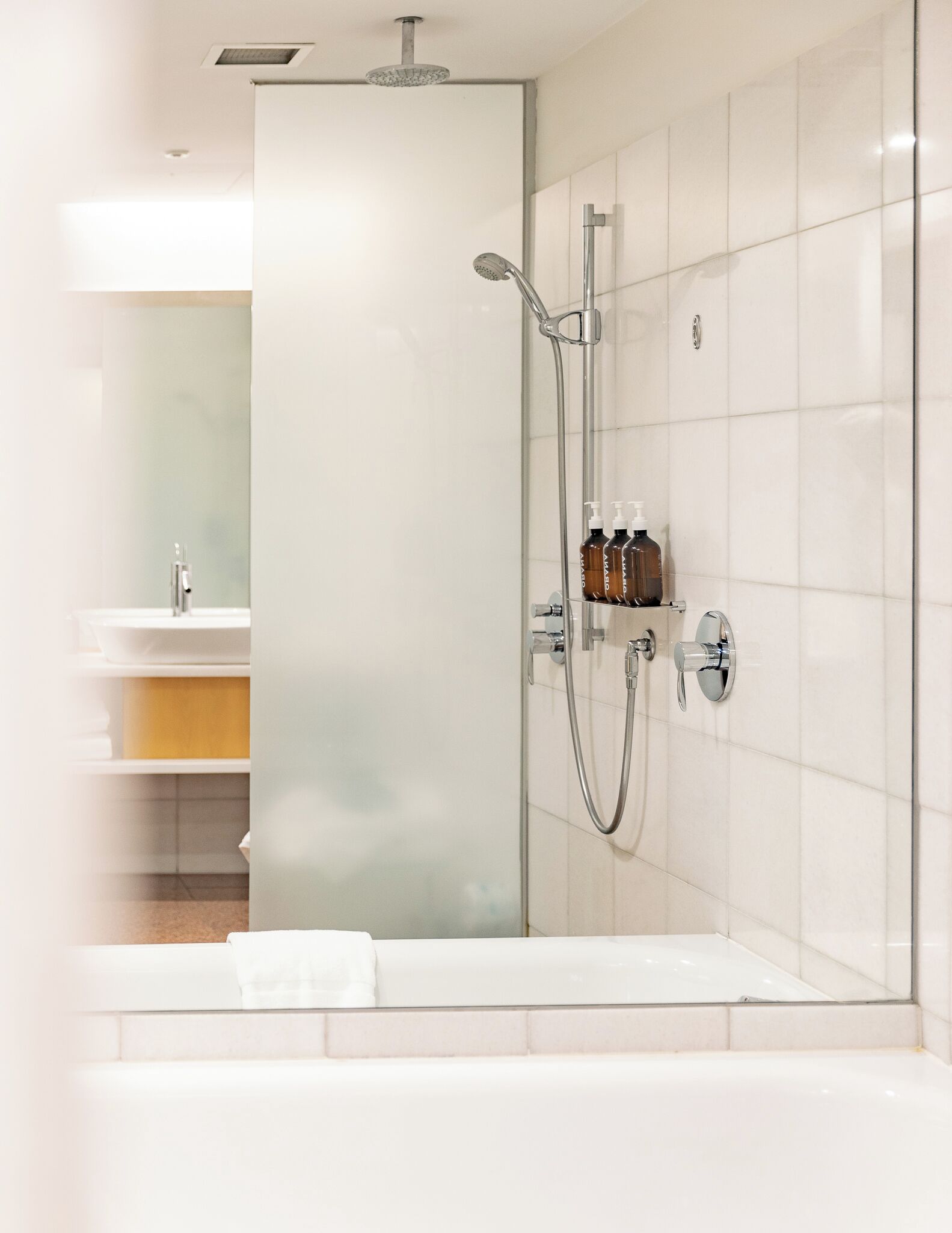 A modern bathroom with a glass shower enclosure, a white bathtub, and a vanity with a mirror.