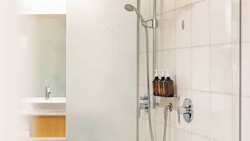 A modern bathroom with a glass shower enclosure, a white bathtub, and a vanity with a mirror.