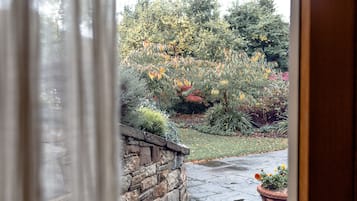 A stone wall and a garden with various plants and trees.
