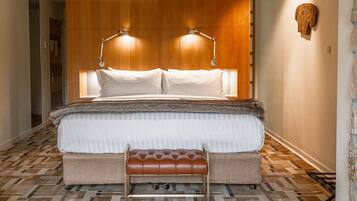 A modern hotel room with a large bed, two bedside lamps, a bench, and a patterned floor.