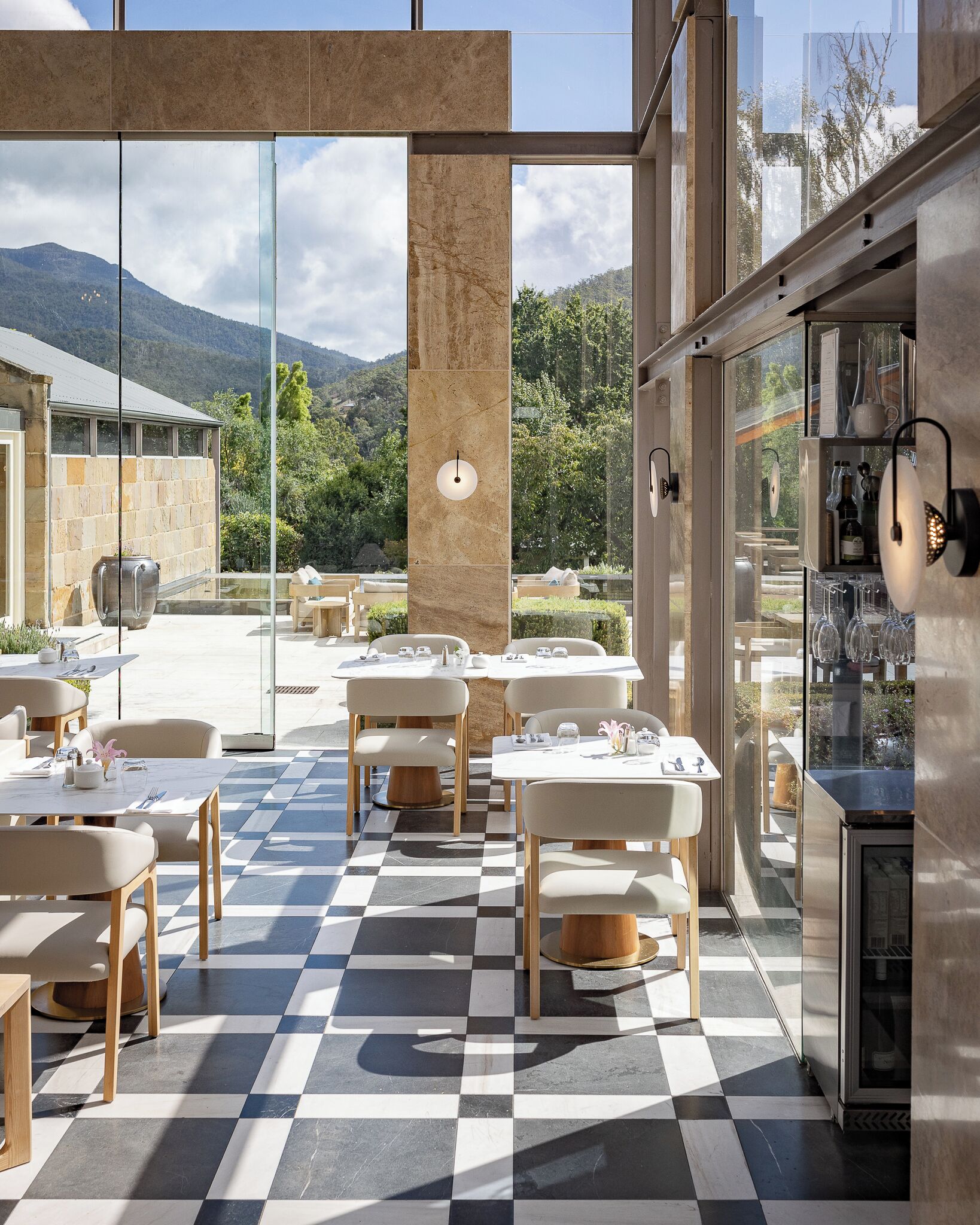 A modern outdoor dining area with checkered flooring and natural light from large windows.