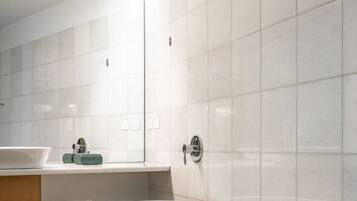 Un baño moderno con una bañera independiente, un banco de madera y un espejo grande.