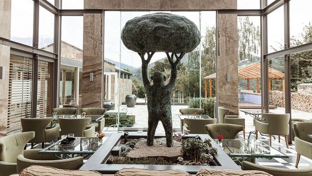 A modern indoor space with a central sculpture, glass tables, and chairs arranged around a central area. - Islington Hotel (South Hobart)