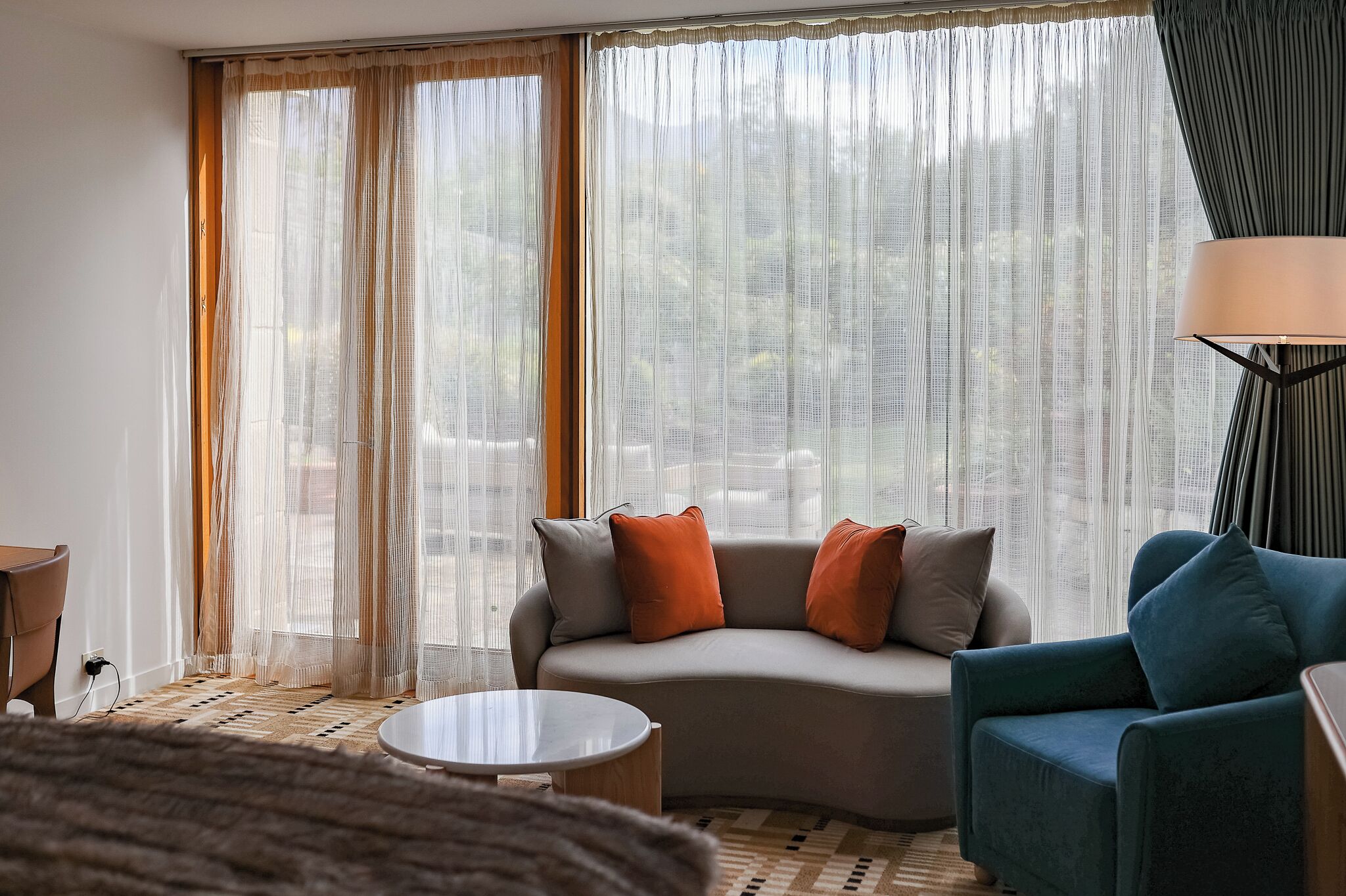 A modern living room with a curved sofa, a round coffee table, and a blue armchair.