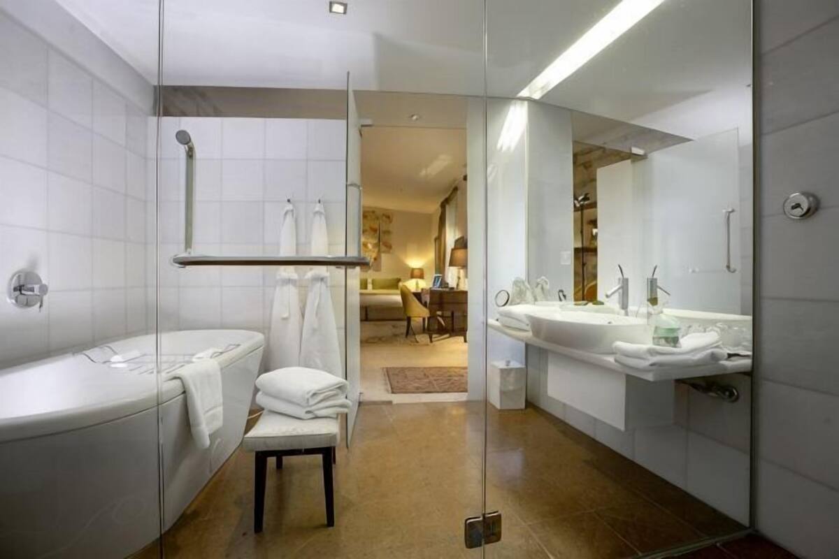 A modern bathroom with a glass shower enclosure, a bathtub, a vanity with a sink, and a mirror.