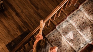 A high-ceiling room with a chandelier, wooden flooring, and patterned rugs.