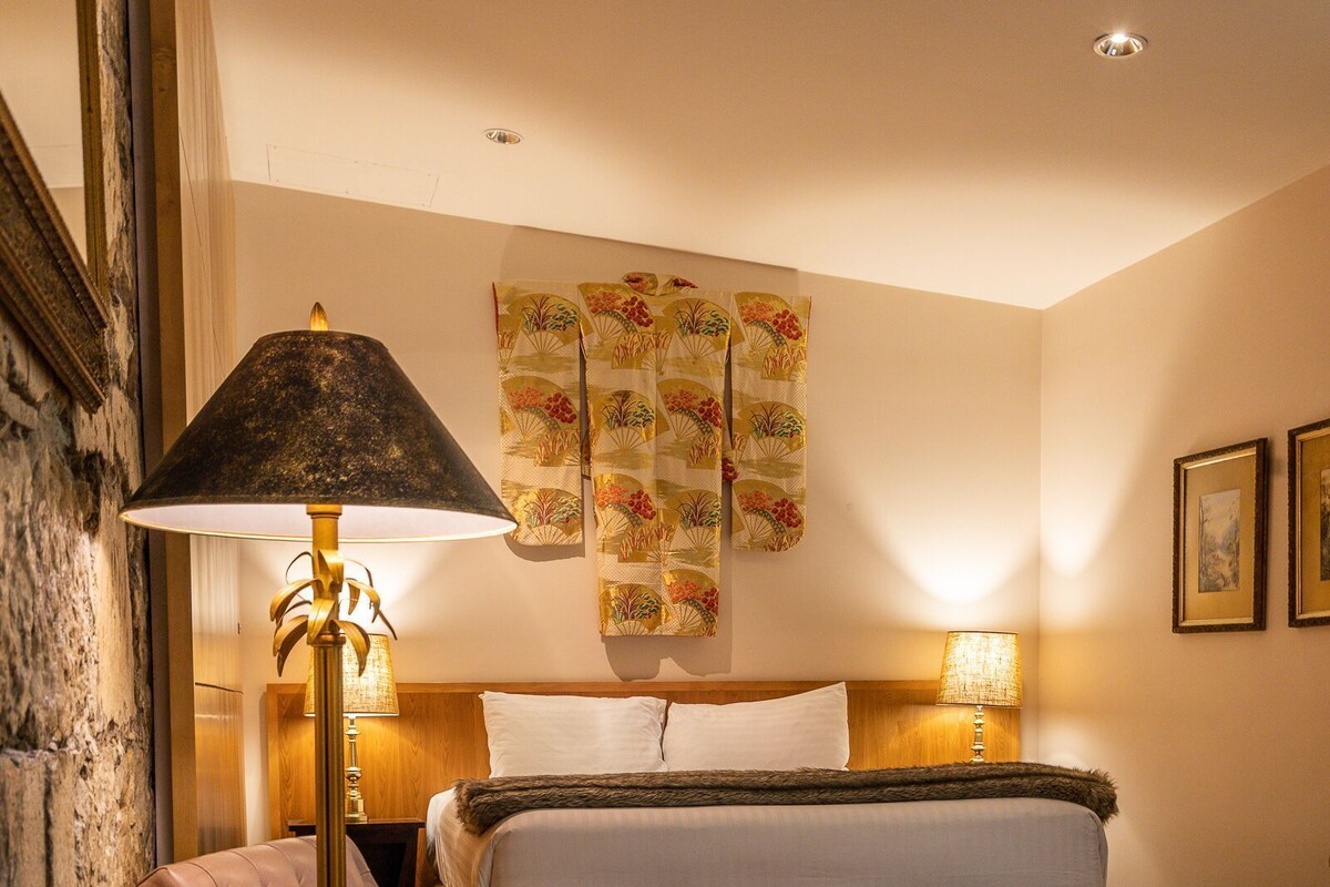 A hotel room with a bed, a chair, a lamp, and a patterned carpet.