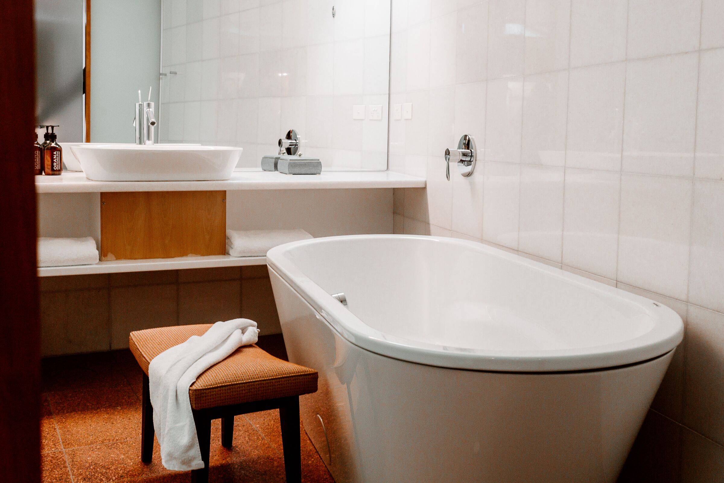 A modern bathroom with a freestanding bathtub, a wooden vanity, and a large mirror.