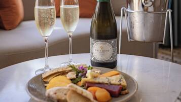 A table with a bottle of wine, two glasses of white wine, a metal bucket, and a plate of food.