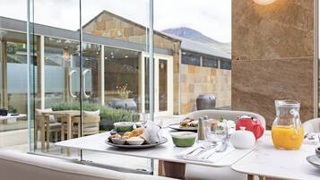 A dining area with a table set for breakfast, including plates, bowls, and a pitcher of orange juice.