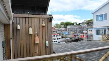 Una terraza de madera con boyas, un puerto deportivo con barcos y edificios al fondo.