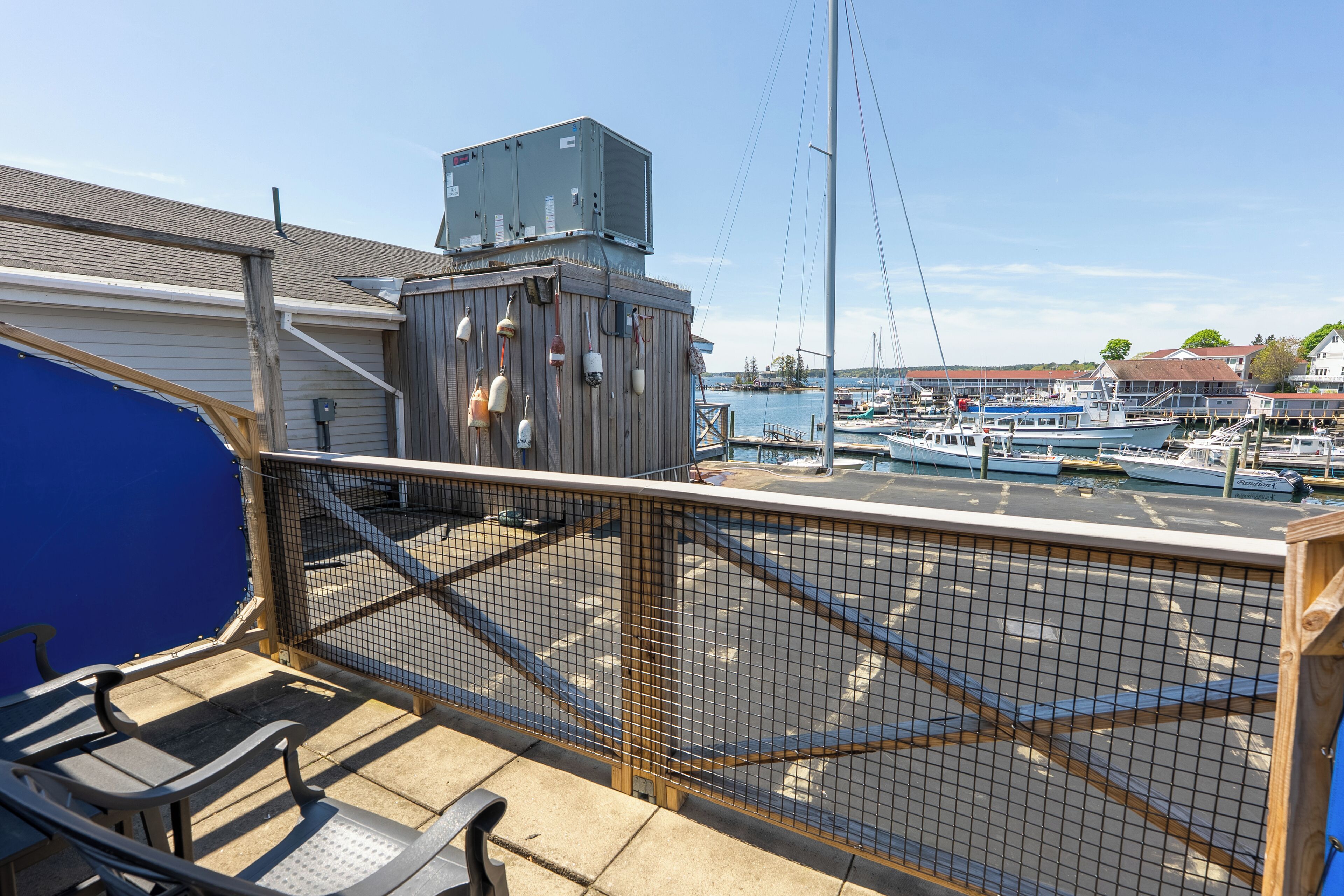 A balcony with a view of a marina, a blue awning, and a metal railing.