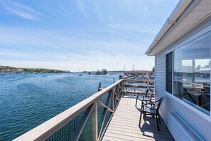 A wooden deck with chairs overlooking a marina with boats. - Fishermans Wharf Inn (Boothbay Harbor)