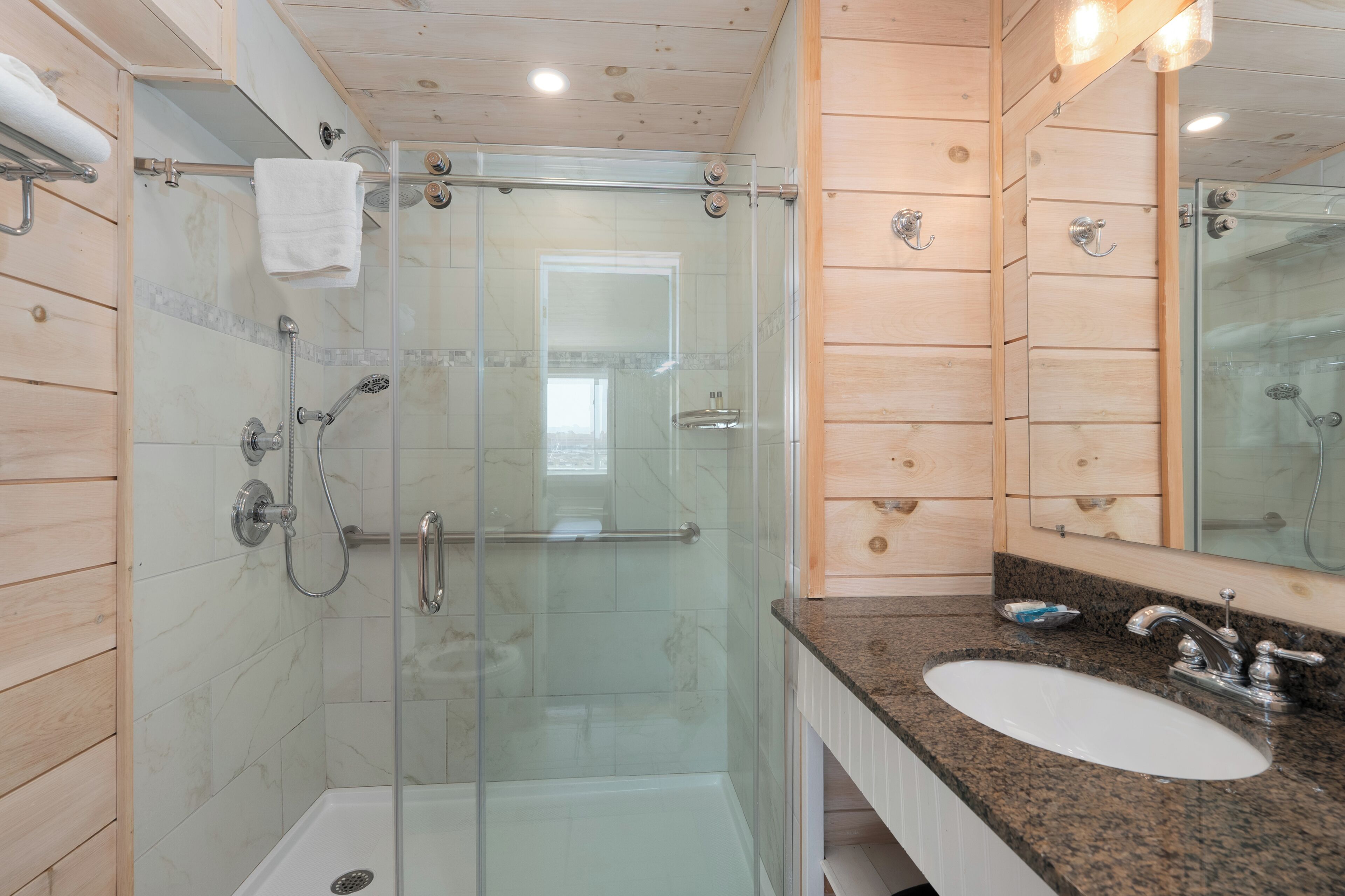 A modern bathroom with a glass-enclosed shower, a white sink, and wooden paneling.