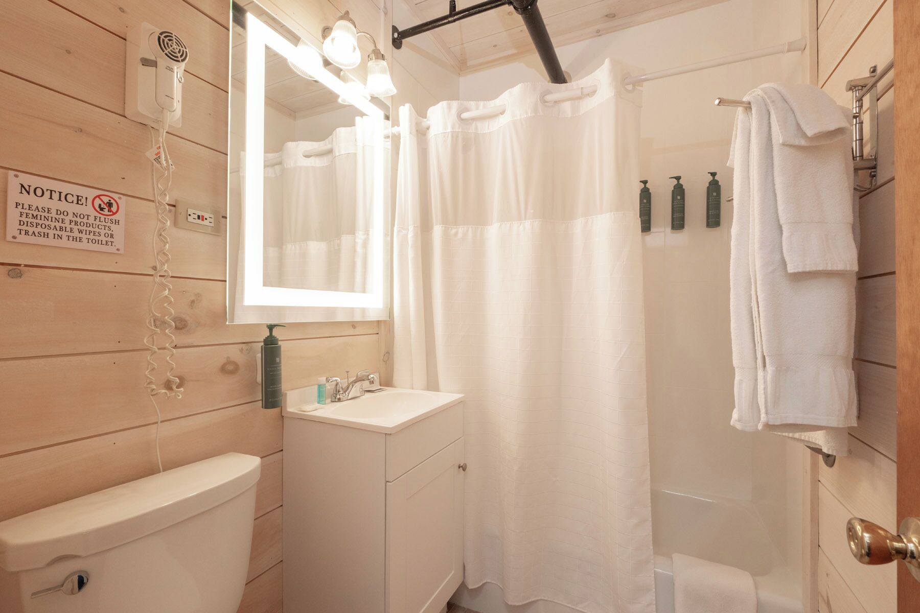 A bathroom with a toilet, sink, mirror, and shower curtain.