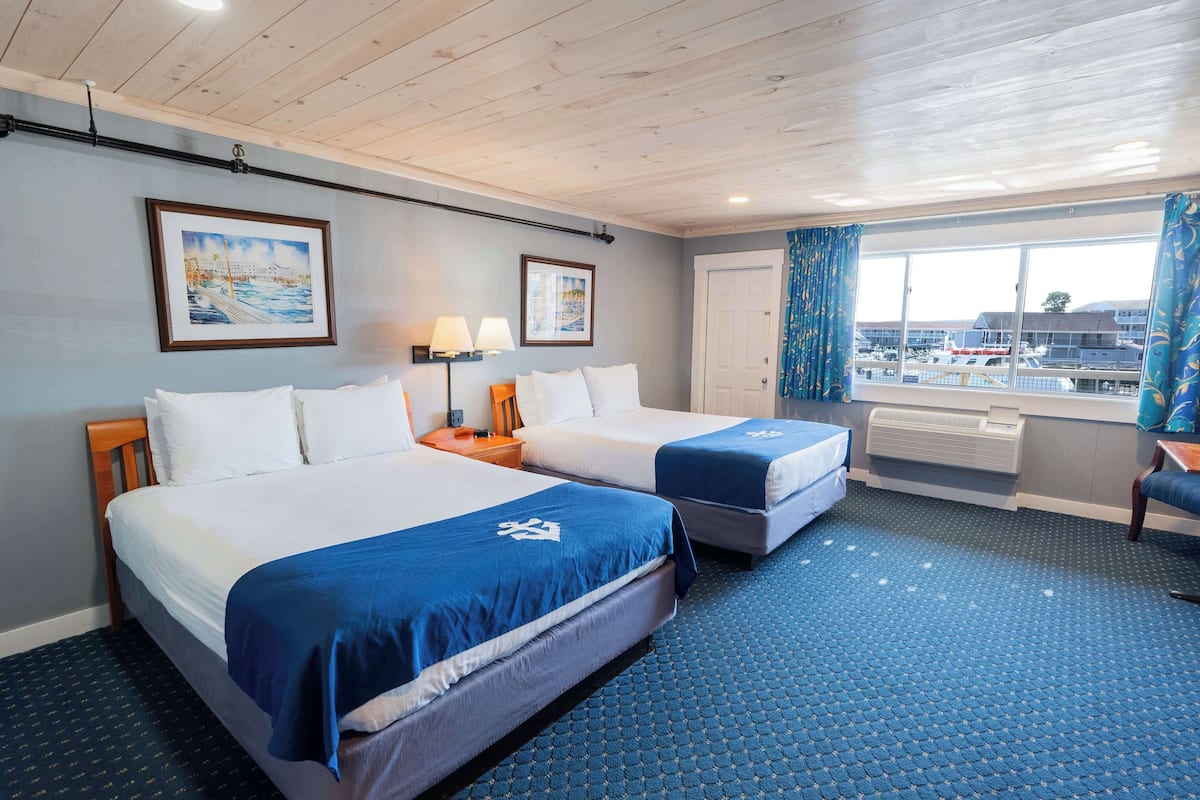 A hotel room with two beds, a large window with a view of the airport, and a ceiling with wooden beams.