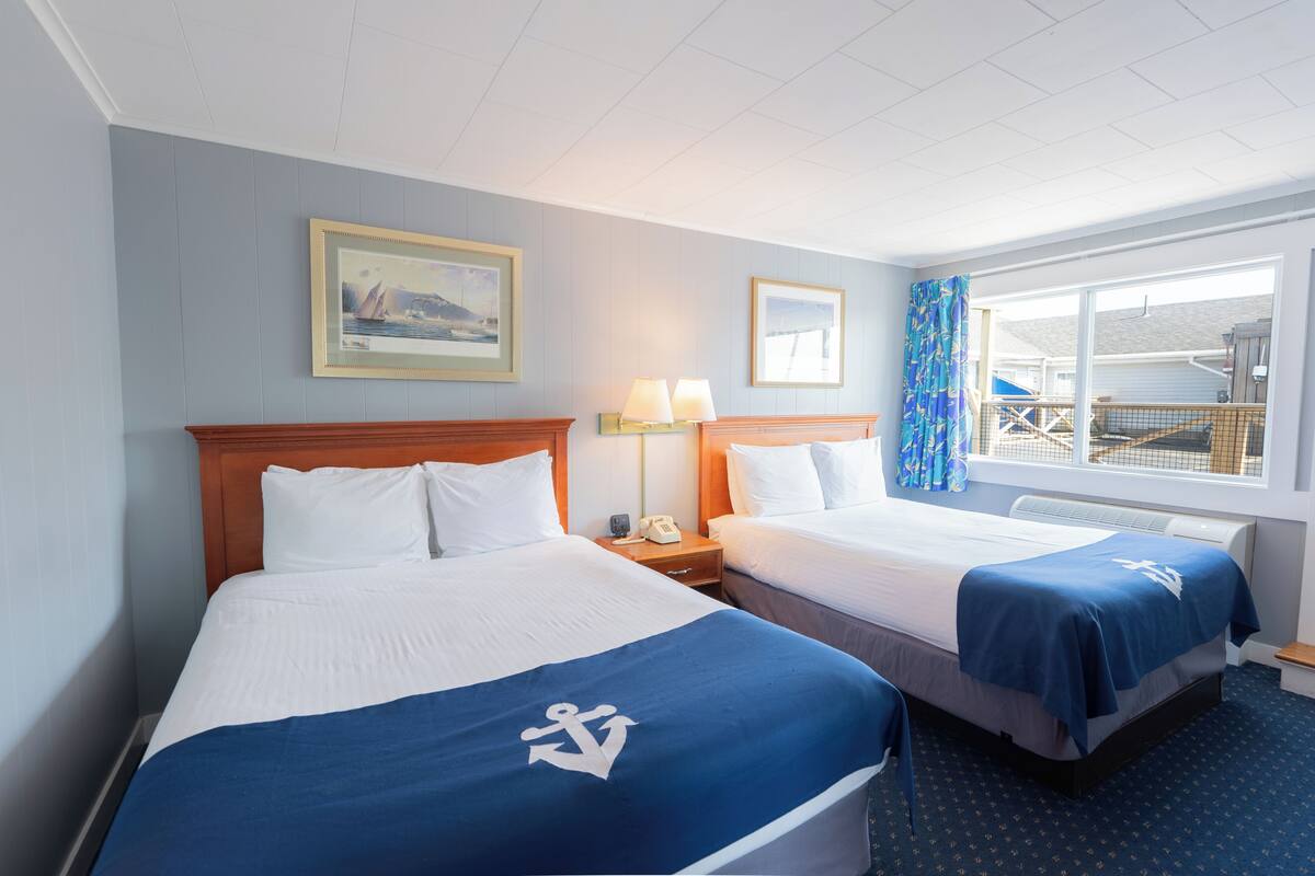 A hotel room with two beds, a large window with a view, and a painting on the wall.