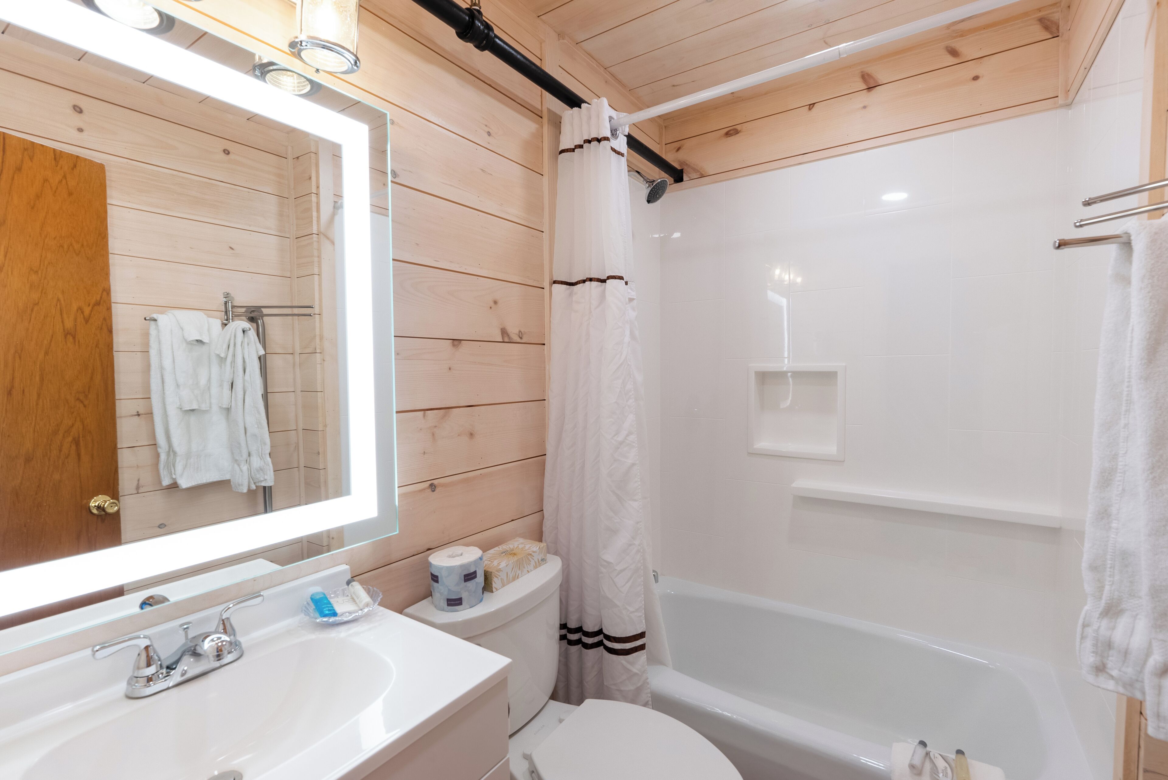 A bathroom with a wooden interior, a white sink, a toilet, and a bathtub.