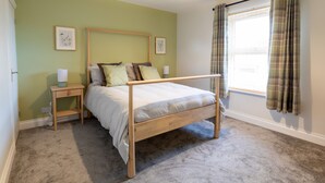 Une chambre à coucher avec un lit en bois, une table de chevet, une lampe et une fenêtre avec des rideaux.