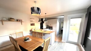 Une cuisine moderne dotée d’un îlot central, d’une table à manger en bois avec des chaises et d’un éclairage suspendu.