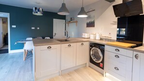 Une cuisine compacte équipée d’un lave-linge, d’un évier et d’un plan de travail en bois.