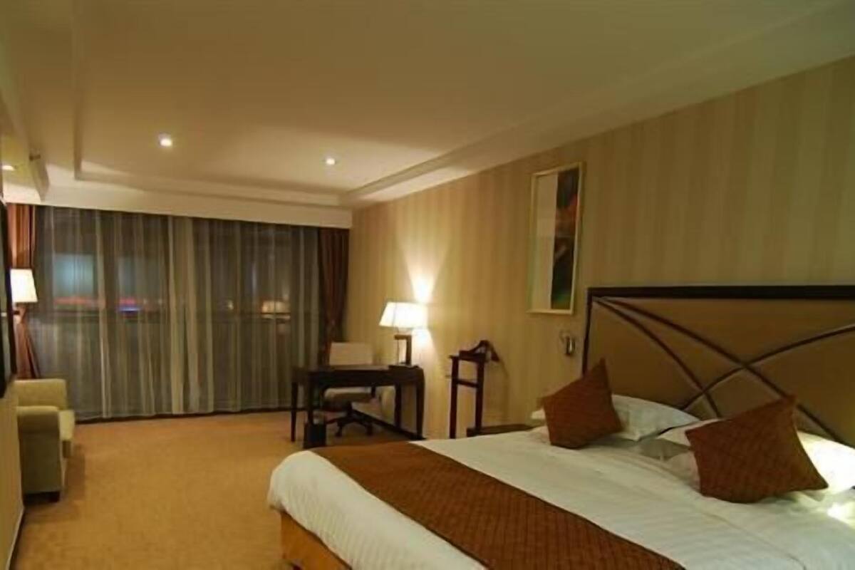 A hotel room with a bed, a desk, a chair, and a television.