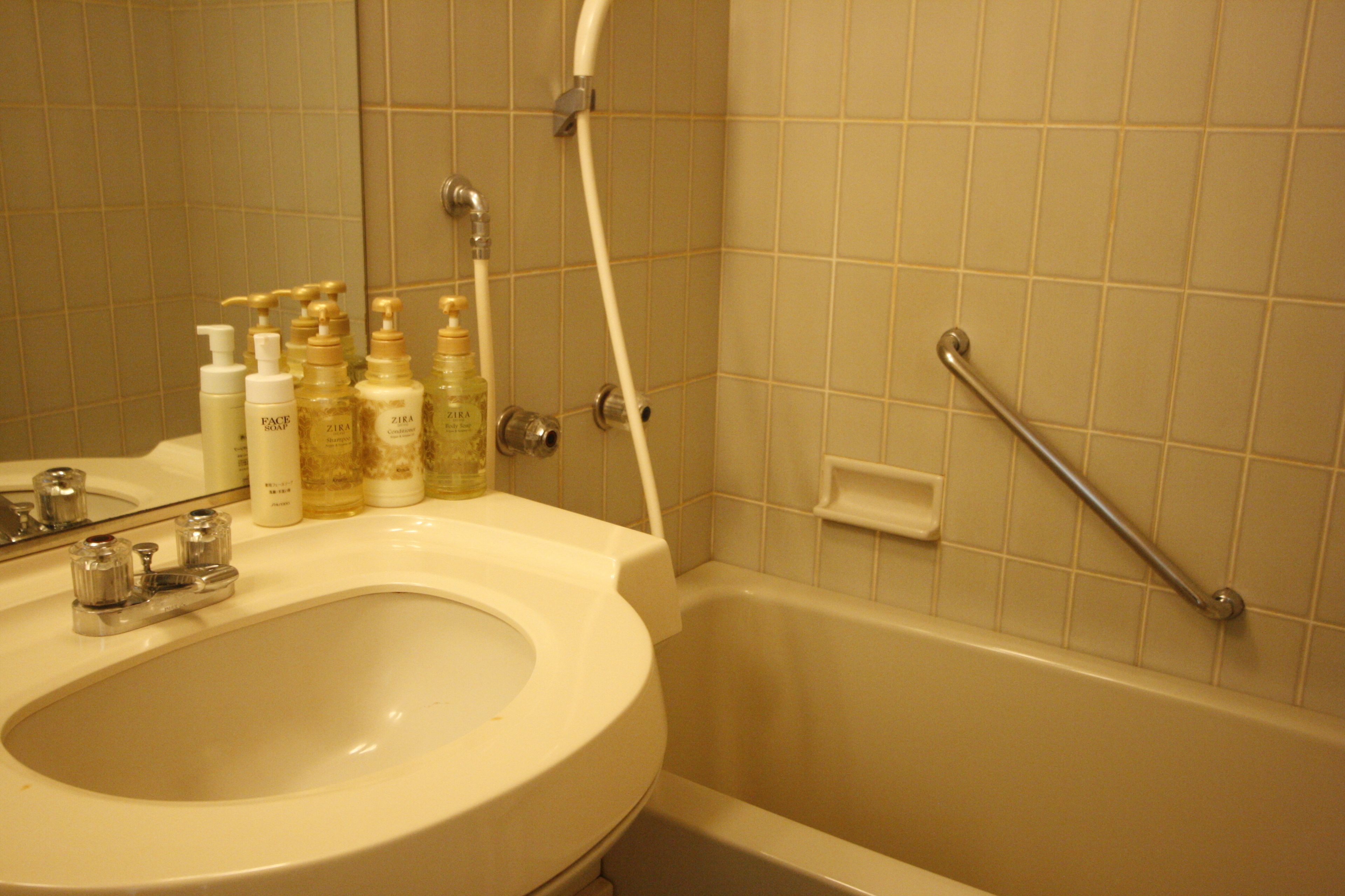 Un baño con lavamanos, espejo y artículos de aseo.