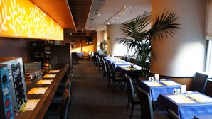 Un restaurante con mesas largas, sillas y una barra con la carta.