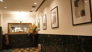 Un vestíbulo con mostrador de recepción, obras enmarcadas en las paredes y un suelo con diseño.