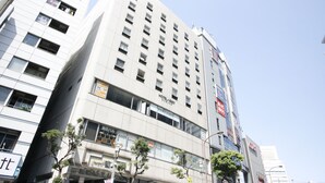 Un hotel de varios pisos con fachada moderna, amplias ventanas y señalización que indica servicios como gimnasio y restaurante.