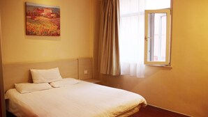 Un dormitorio con cama, un cuadro en la pared y una ventana con cortinas.