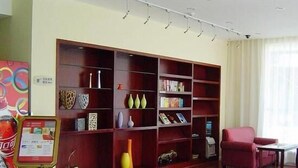 Una biblioteca con estanterías, una máquina expendedora y una silla roja.