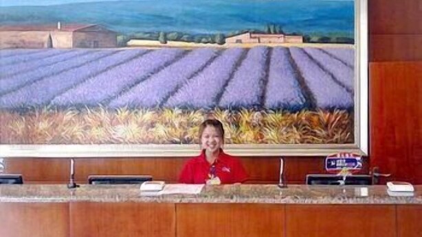 Un mostrador de recepción con un cuadro grande de un campo de lavanda al fondo.