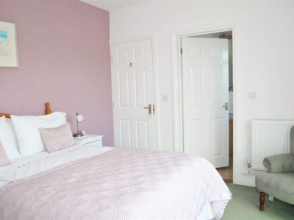 A bedroom with a bed, nightstands, a chair, and two doors.