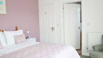 A bedroom with a bed, nightstands, a chair, and two doors.