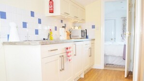 A kitchen with white cabinets, a microwave, and a red fire extinguisher. - Quixhill - Denstone - Dove Meadow B & B (Uttoxeter)