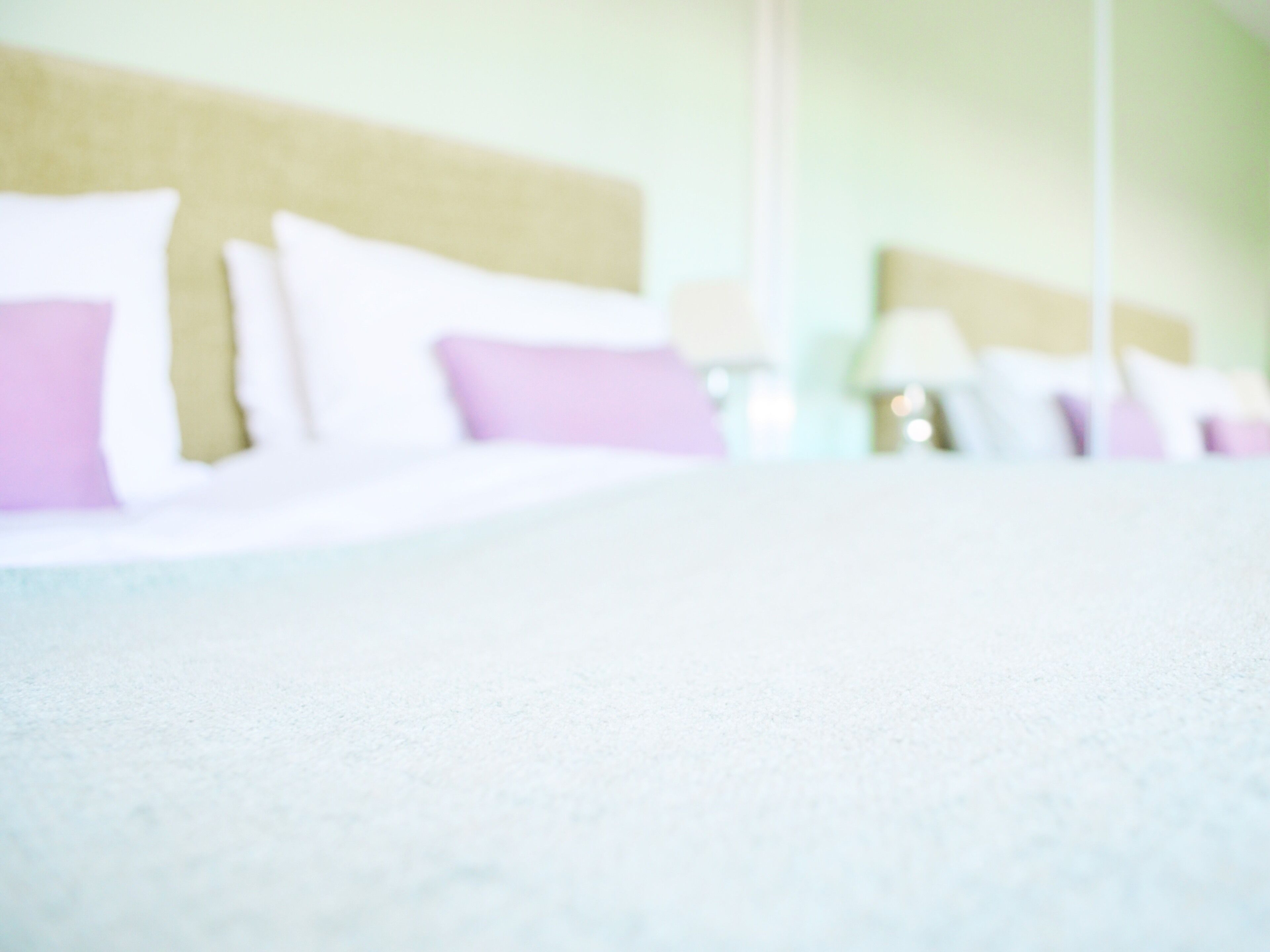 Habitación de hotel desenfocada con una cama y almohadas.